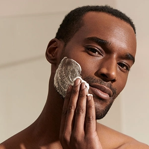 Homem aplicando produto de skincare no rosto.